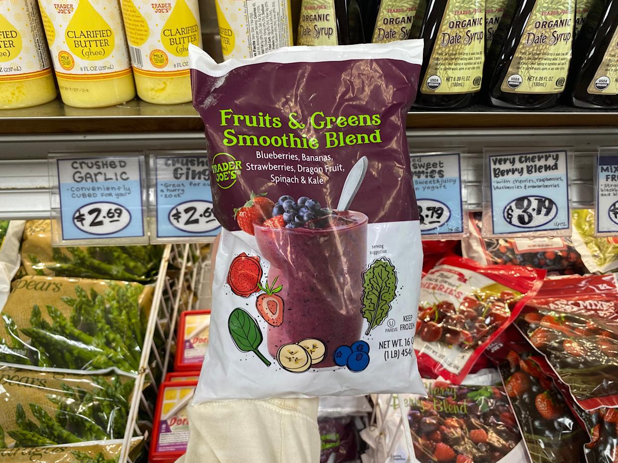 hand holding a bag of frozen smoothie blend in the freezer aisle at trader joes