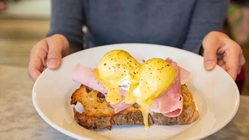 Female hands holding plate with egg Benedict, breakfast meal