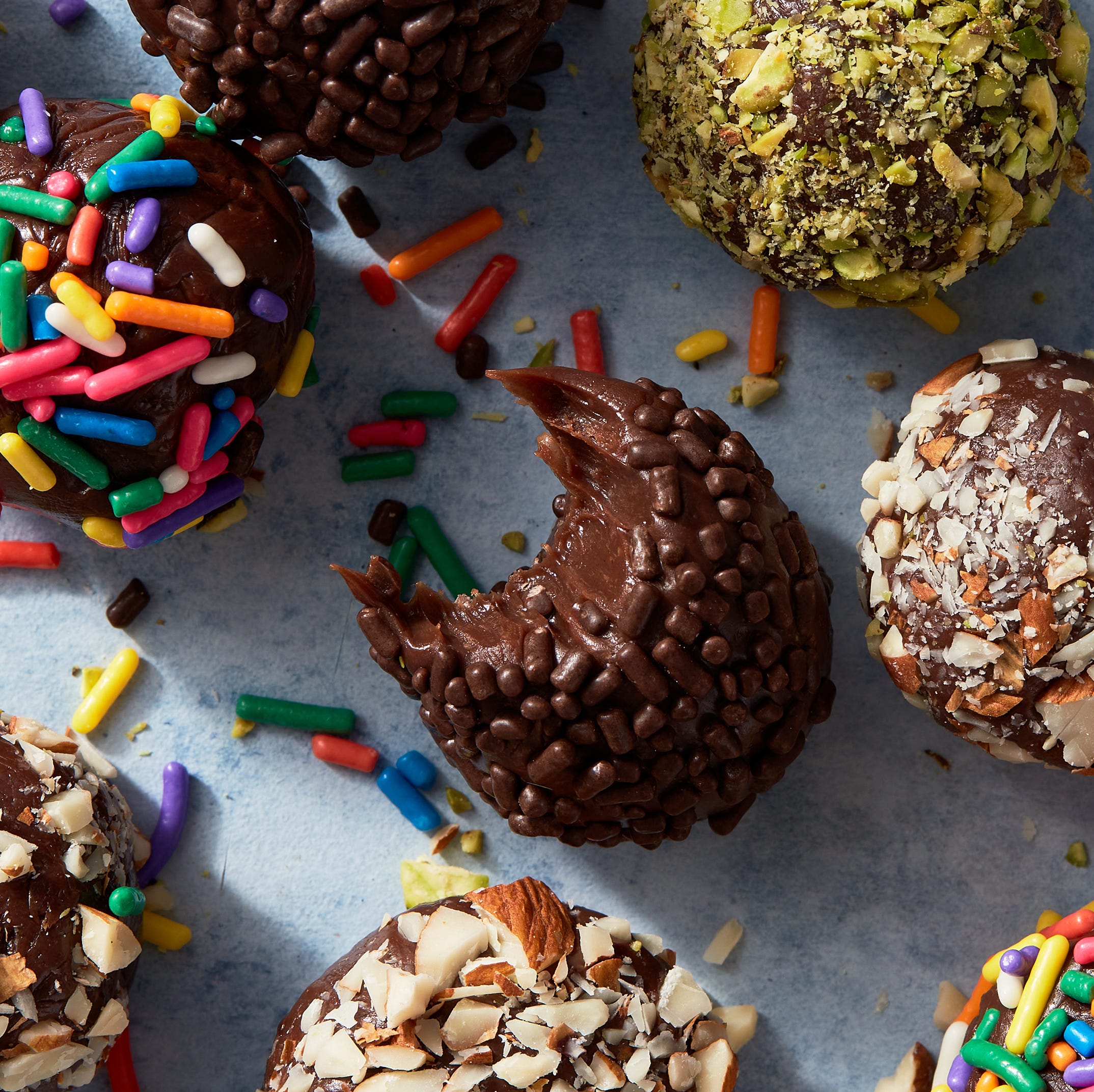 brigadeiros covered in chocolate and rainbow sprinkles, and chopped pistachios and almonds
