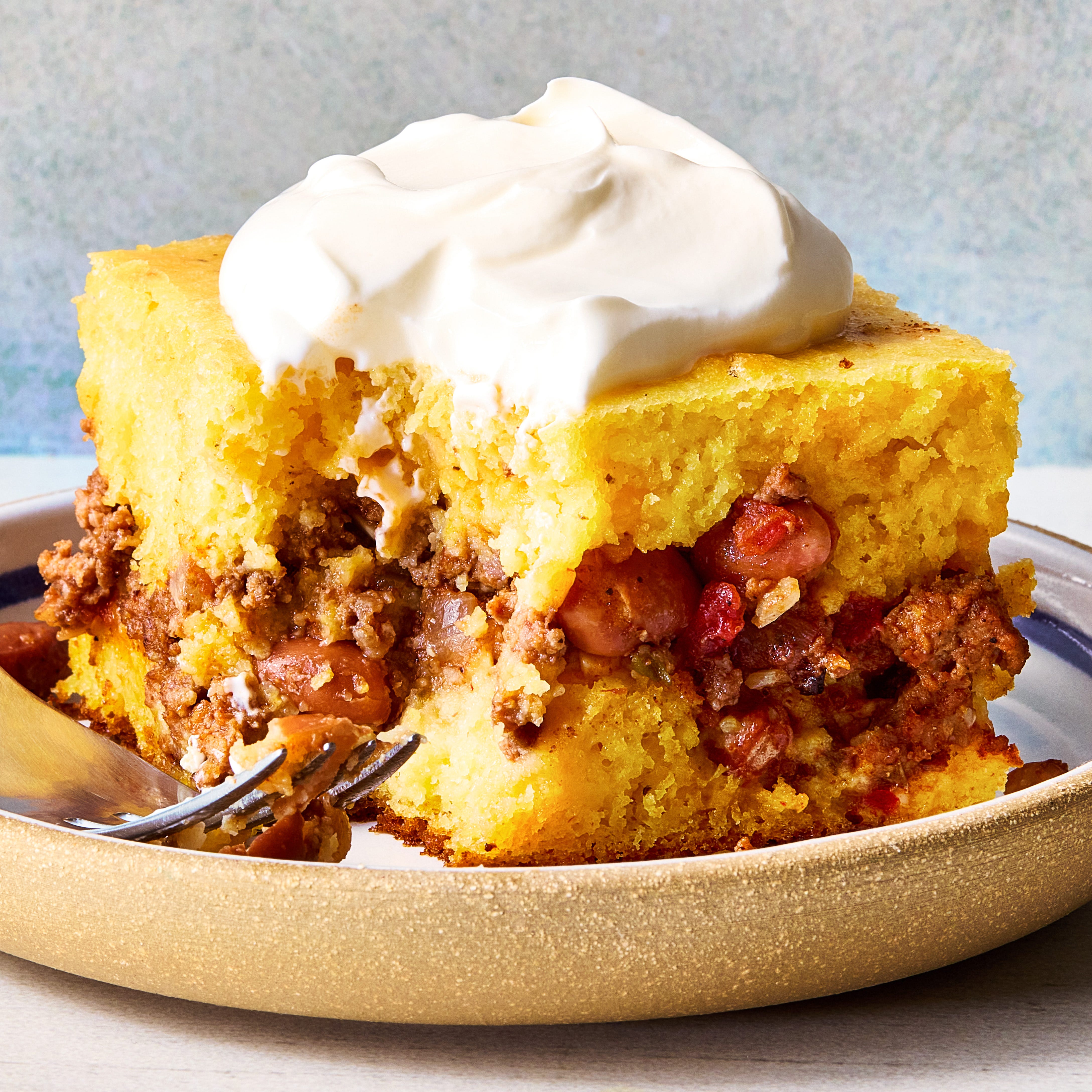 cornbread in a casserole dish with a layer of chili in the middle