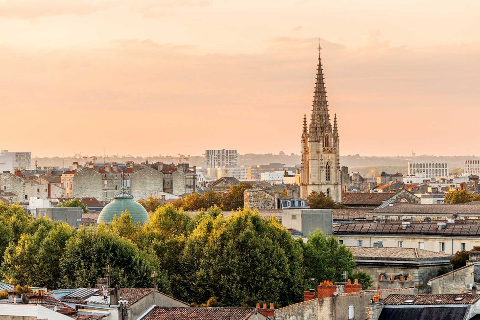 City skyline with a prominent cathedral spire at sunset.