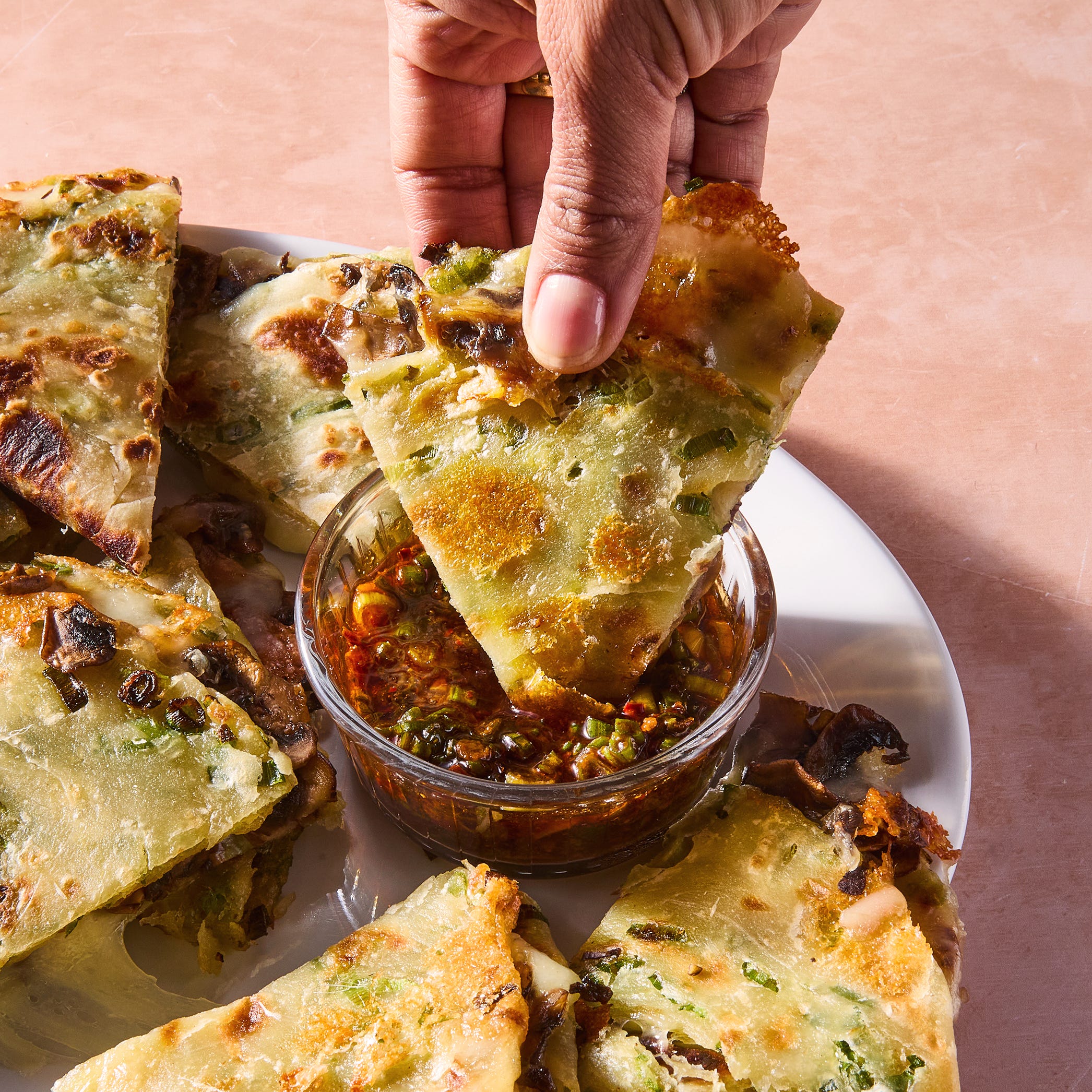 flaky scallion pancakes are fried to golden brown perfection then transformed into quesadillas stuffed with melty mozzarella and umami packed spiced mushrooms and paired with a tangy soy scallion dipping sauce