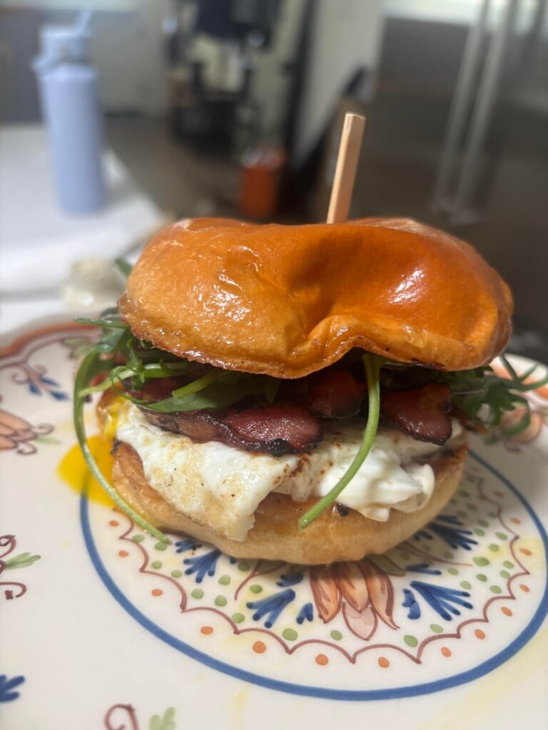 Bacon, egg, wild arugula, and truffle aioli breakfast sando on a brioche bun