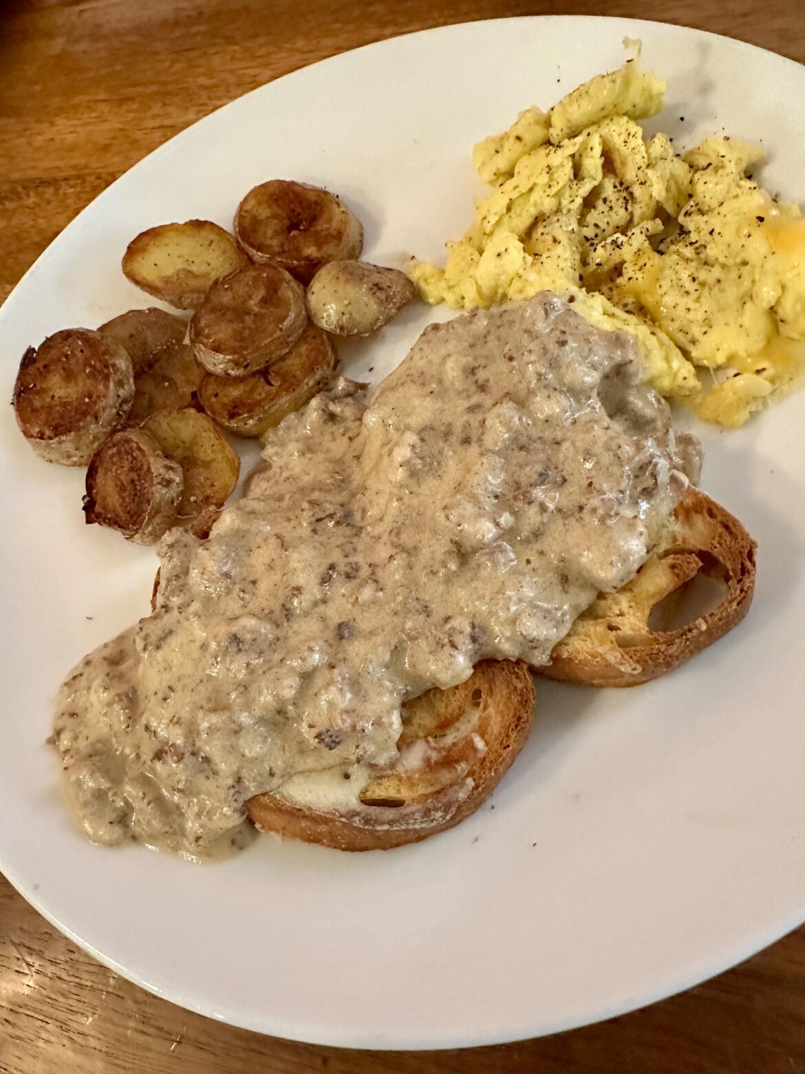 Scrambled Eggs woth Cheddar, Potatoes, Asiago Sliced Loaf toasted with Cheese, covered with Sausage Gravy