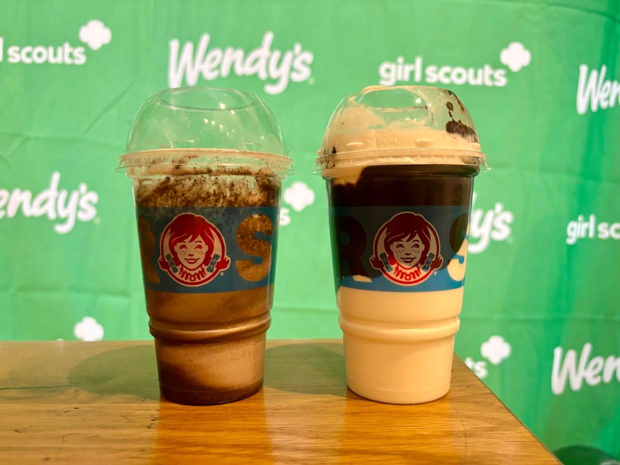 two frosty beverages on a wooden table with a branded backdrop