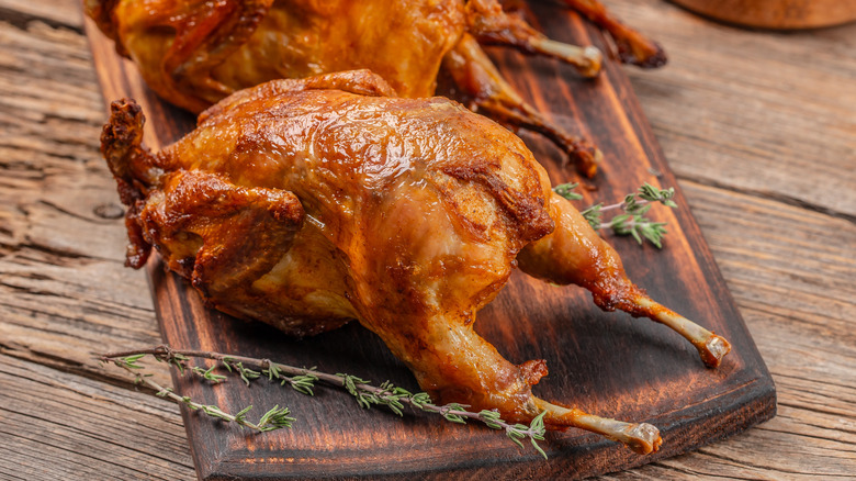 Whole roast quails on a wooden board