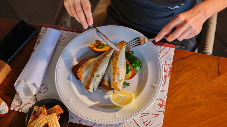 woman eating fish on vegetables