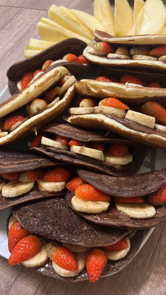 Pancakes with nutella, banana and strawberry. Half of pancakes are with cacao