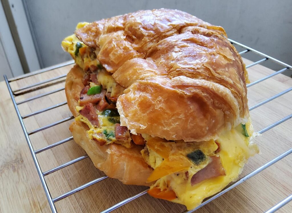 Turned a ham and sweet pepper omelette into a cheesy croissant breakfast sandwich.