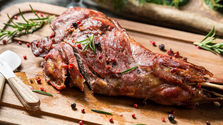 Cooked game meat on a cutting board seasoned with herbs and spices