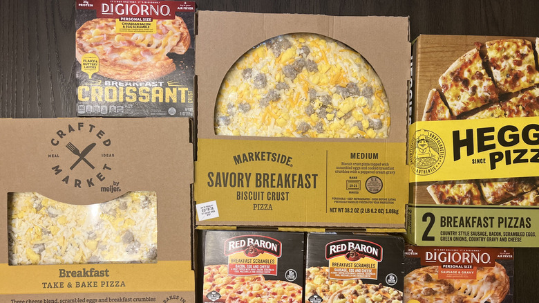 7 different store-bought breakfast pizzas in boxes.