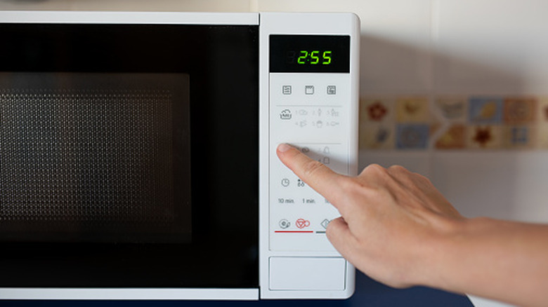 Person pressing buttons on a microwave