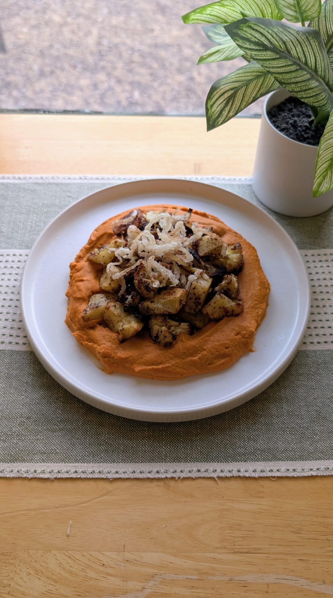 Roasted red pepper hummus topped with crispy greek potatoes and cauliflower 😺