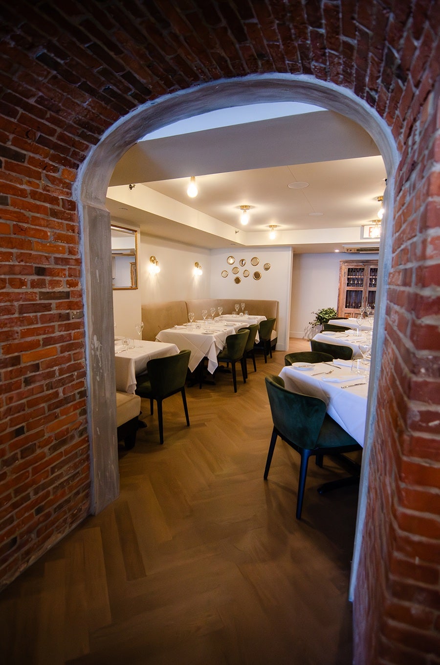 A white-tablecloth restaurant interior, photographed through an exposed brick archway.