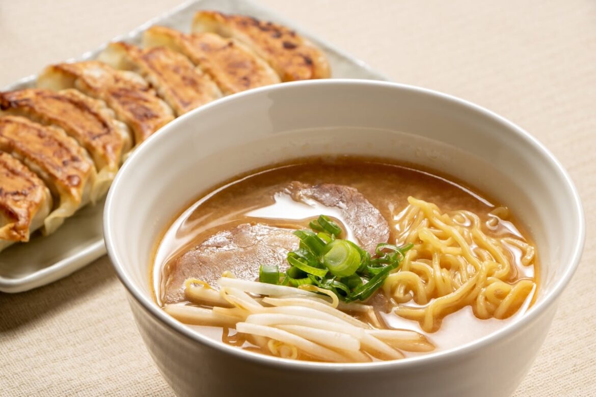Bowl of ramen with gyoza behind it on a separate platter