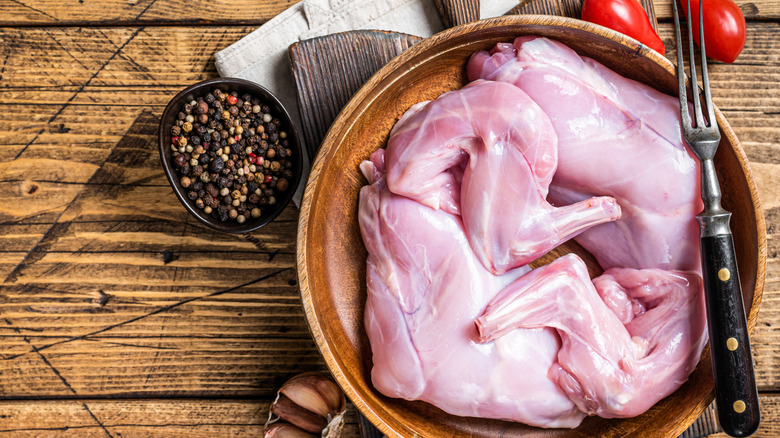 Raw rabbit meat on a plate on a wooden table