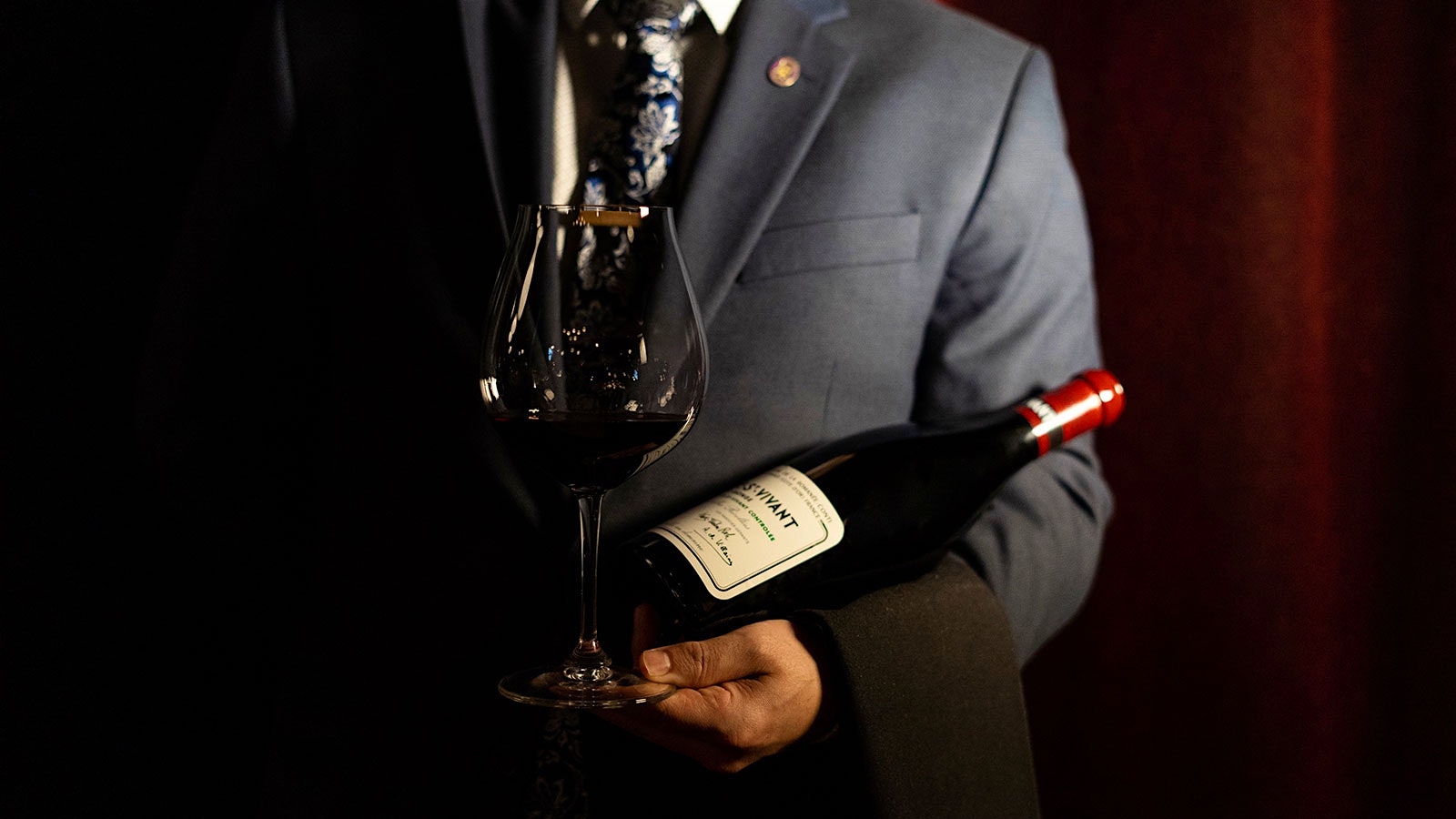  A waiter holding a bottle and glass of Burgundy at Marcel