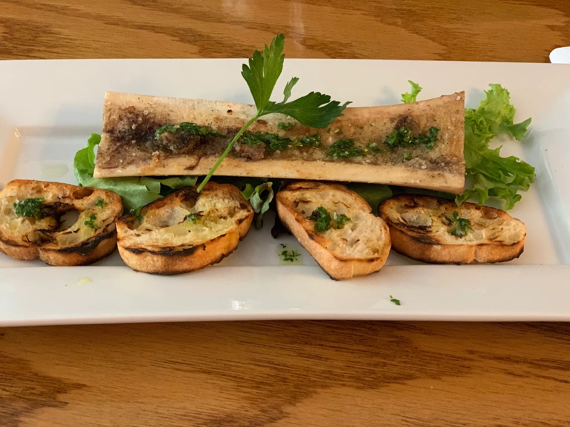 A bone marrow dish with toasts on a plate.