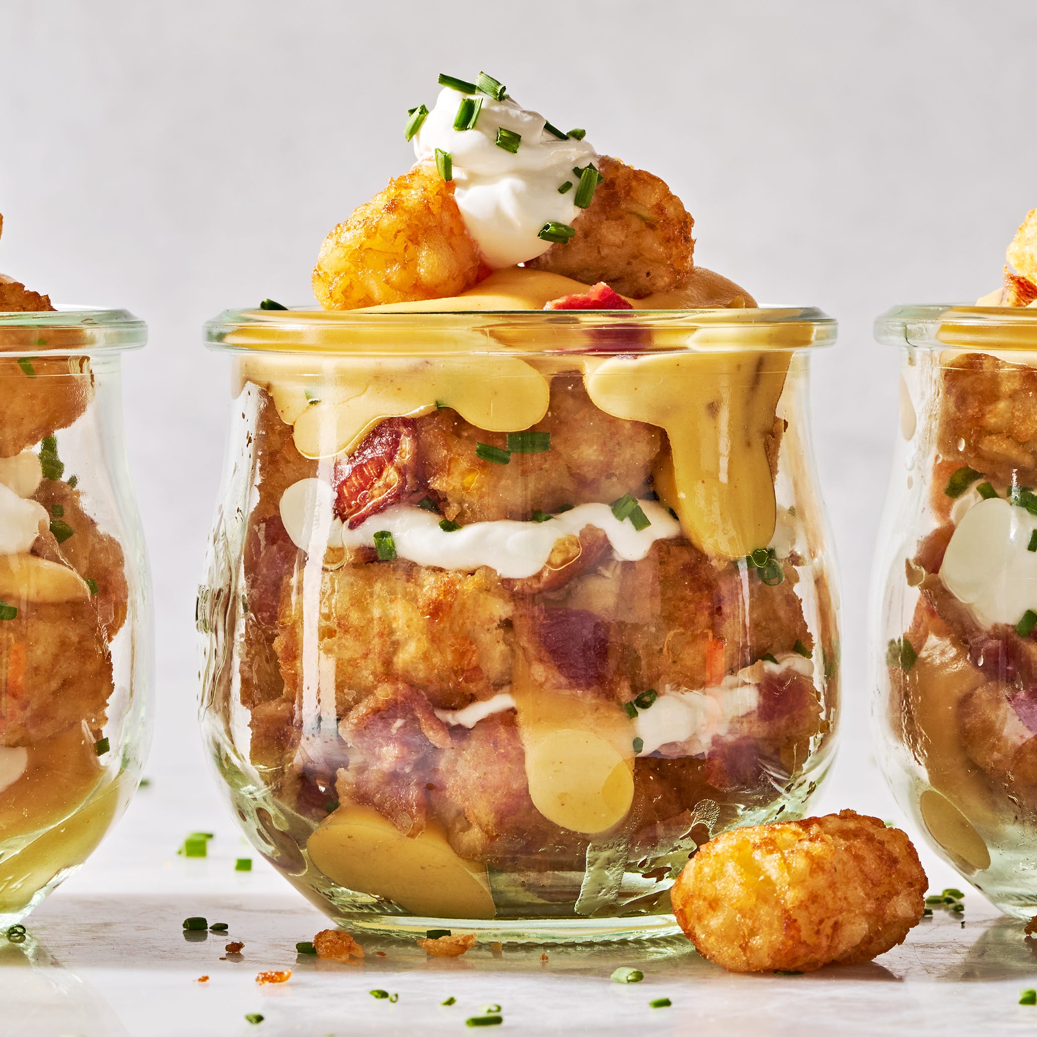 tater tots in a mason jar layered with sour cream, cheese, bacon, and chives
