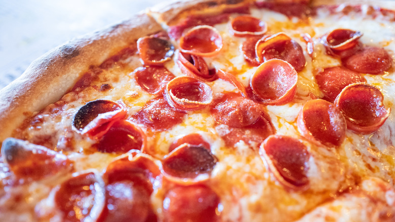 Pepperoni pizza on a light background with some pepperoni slices charred