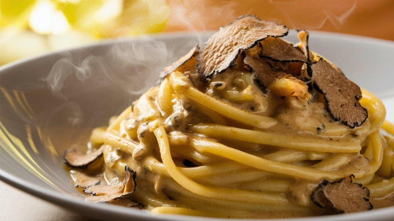 A bowl of pasta garnished with shaved truffle