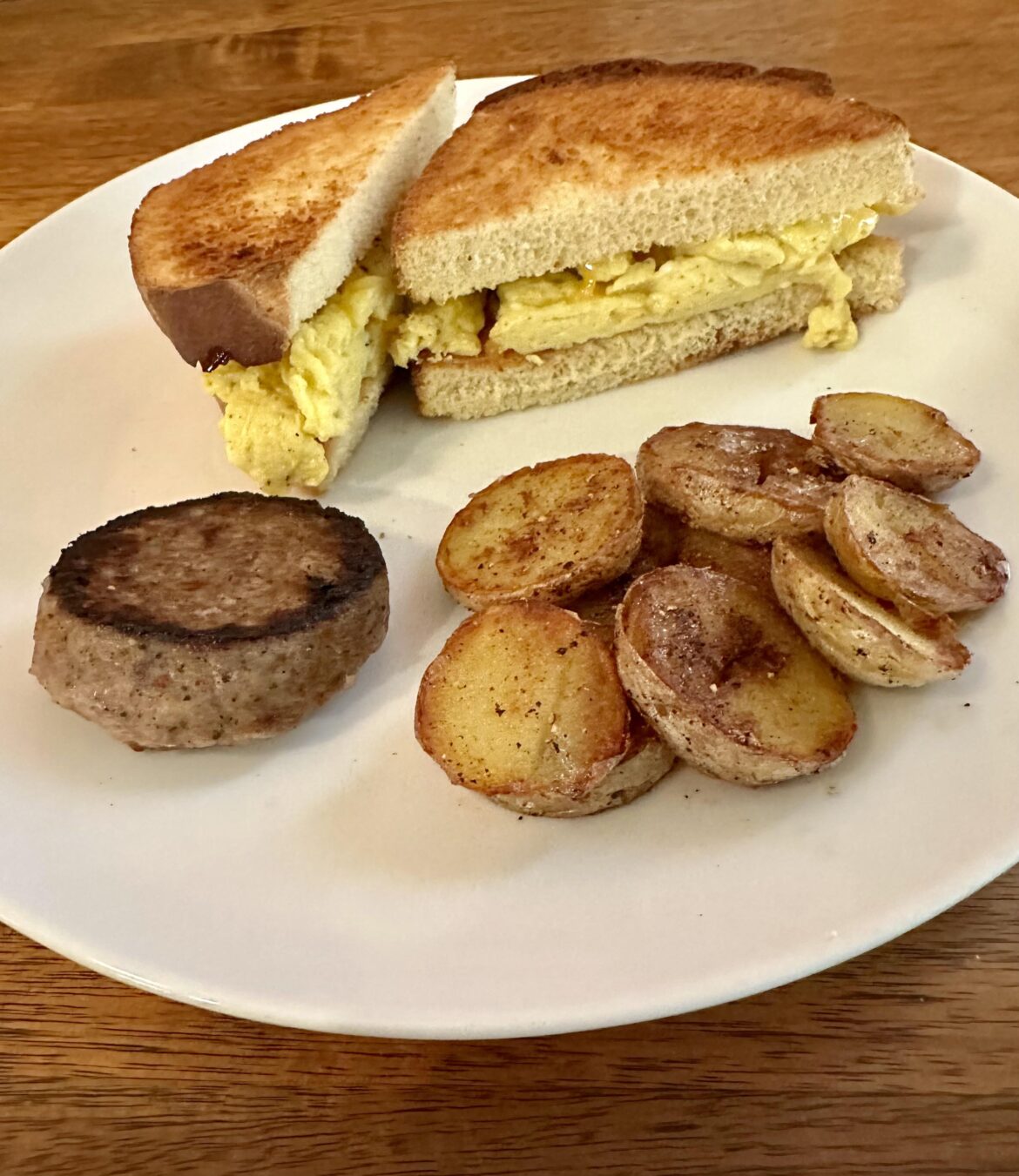Scrambled Eggs & Cheddar Sandwich with Sausage Patty and Fried Potatoes