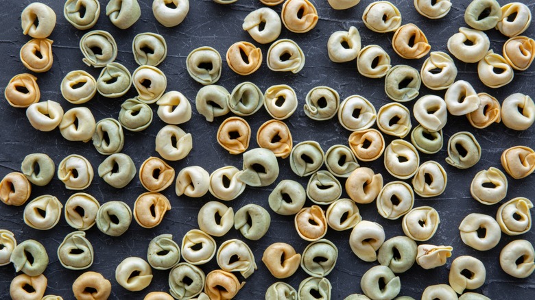 Dried tri-colored tortellini on dark background