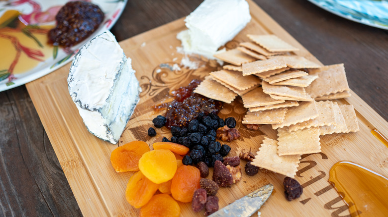 cheese plate with dried fruit, crackers, and spilled honey