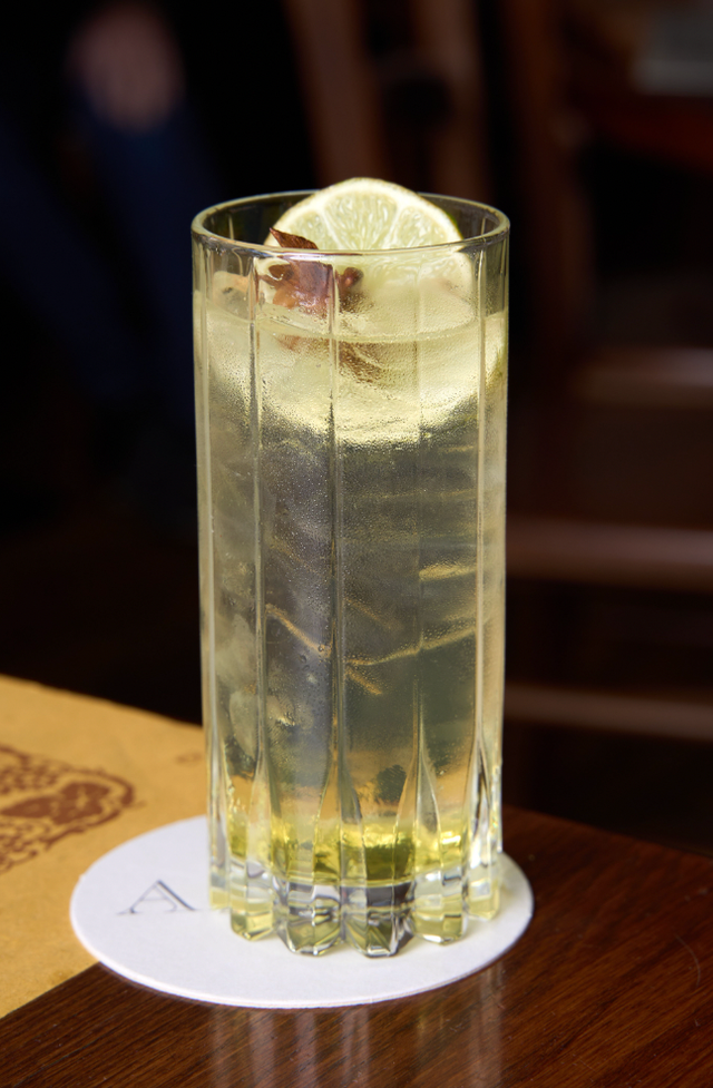 a tall drink with lime slices on a coaster