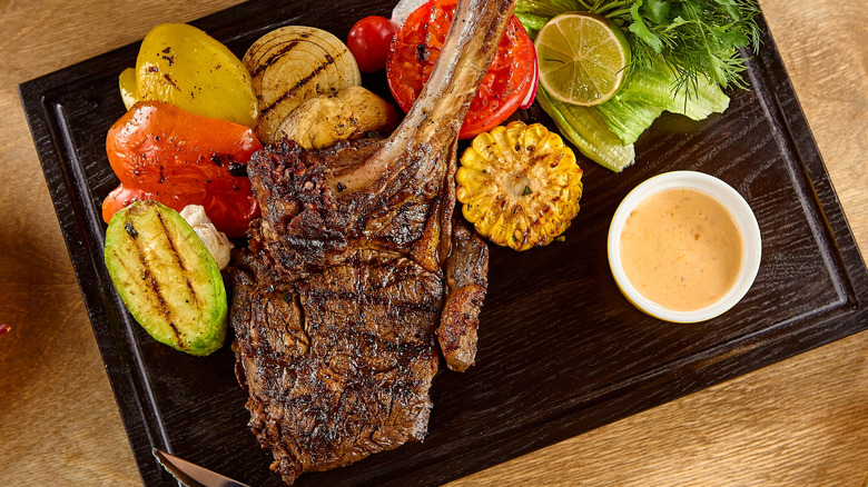 A bone-in yak steak with vegetables on a platter