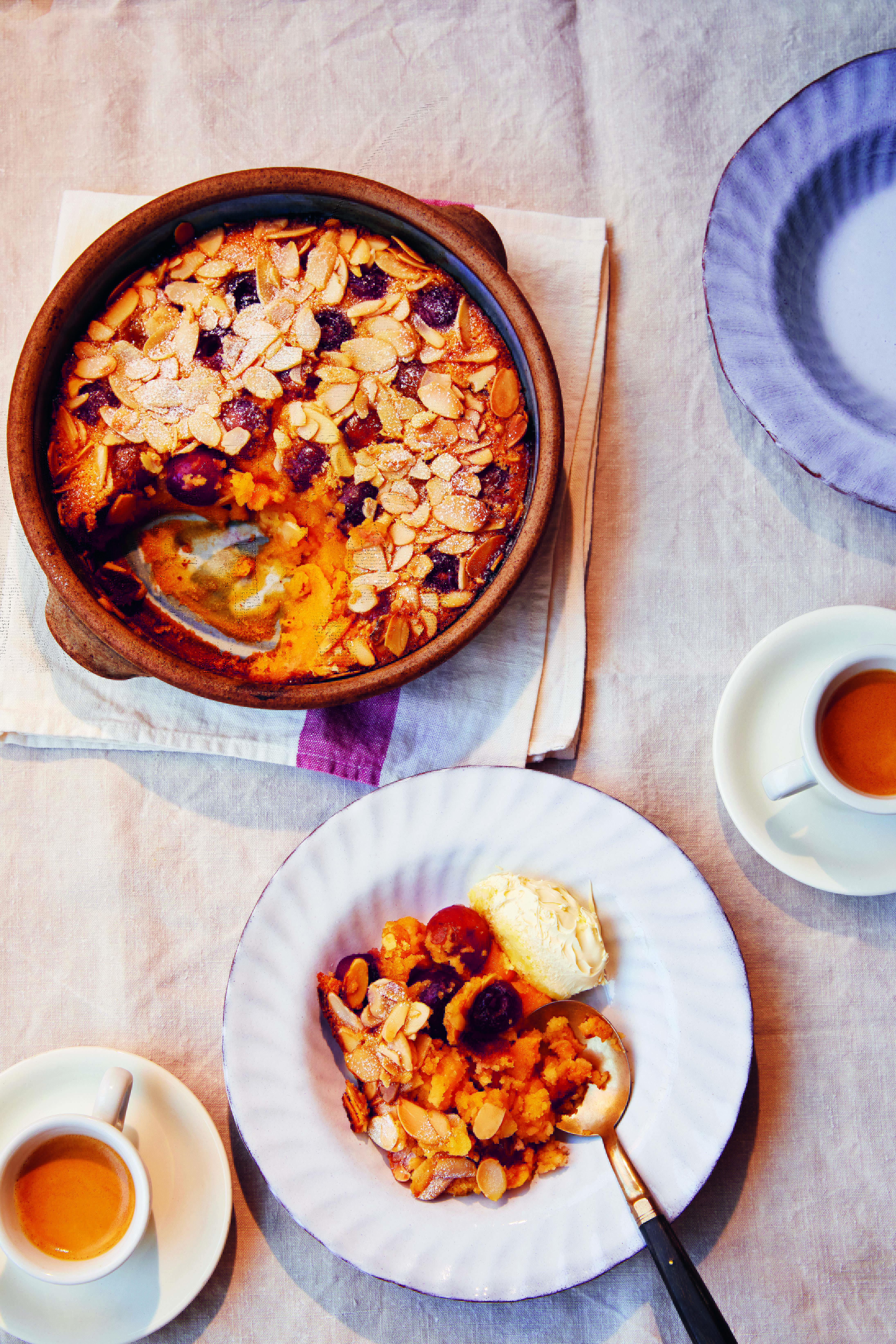 Cherry and Almond Clafoutis in a baking dish and served on a plate with ice cream.