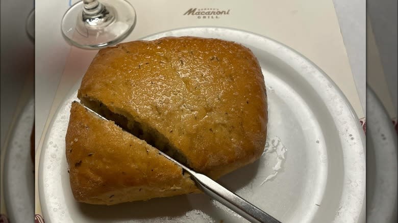 Knife slicing into loaf of Macaroni Grill's signature rosemary bread.