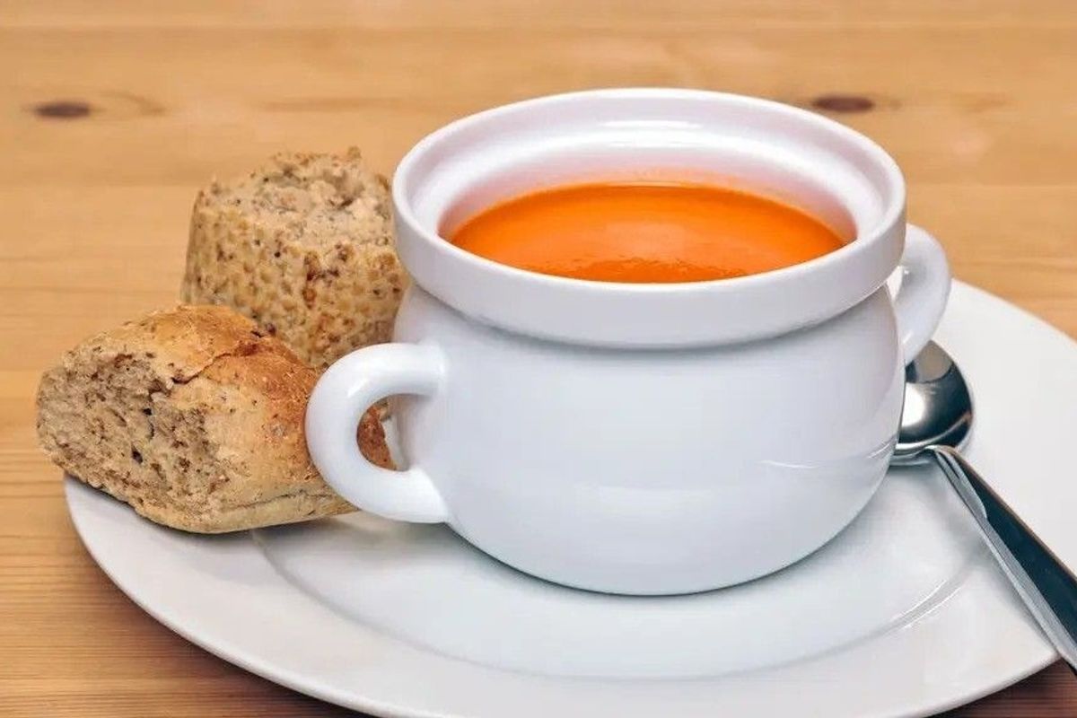 A bowl of soup with a side of bread on a plate 
