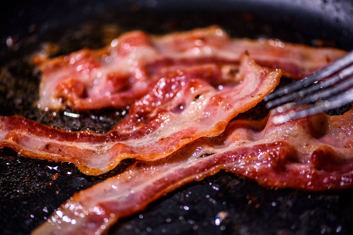 Bacon slice being cooked on a frying pan. Close up