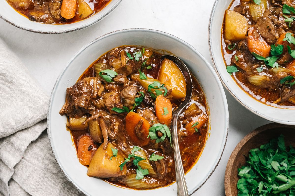 Traditional Irish stew served in a white plate with a silver spoon on a tablecloth