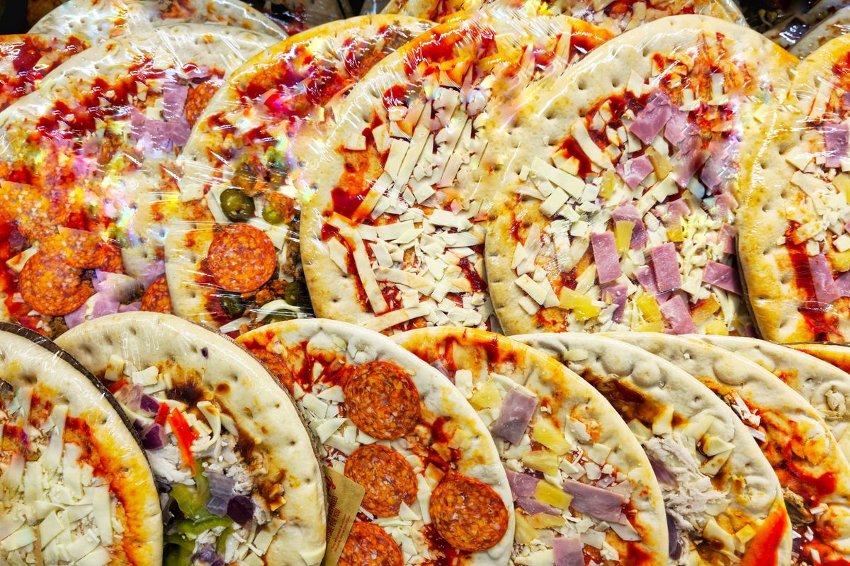 Display of fresh pizzas in a row at the supermarket.