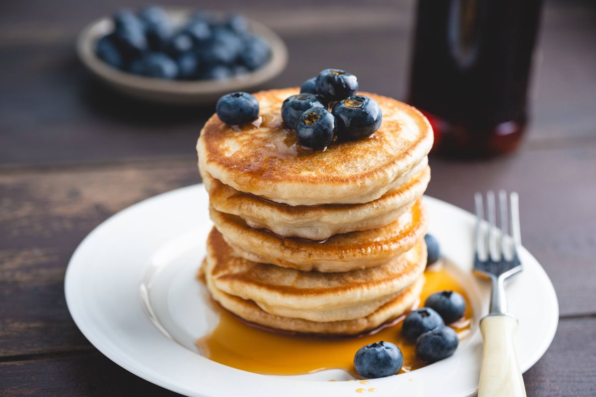 Stack of fluffy buttermilk pancakes with blueberries, maple syrup