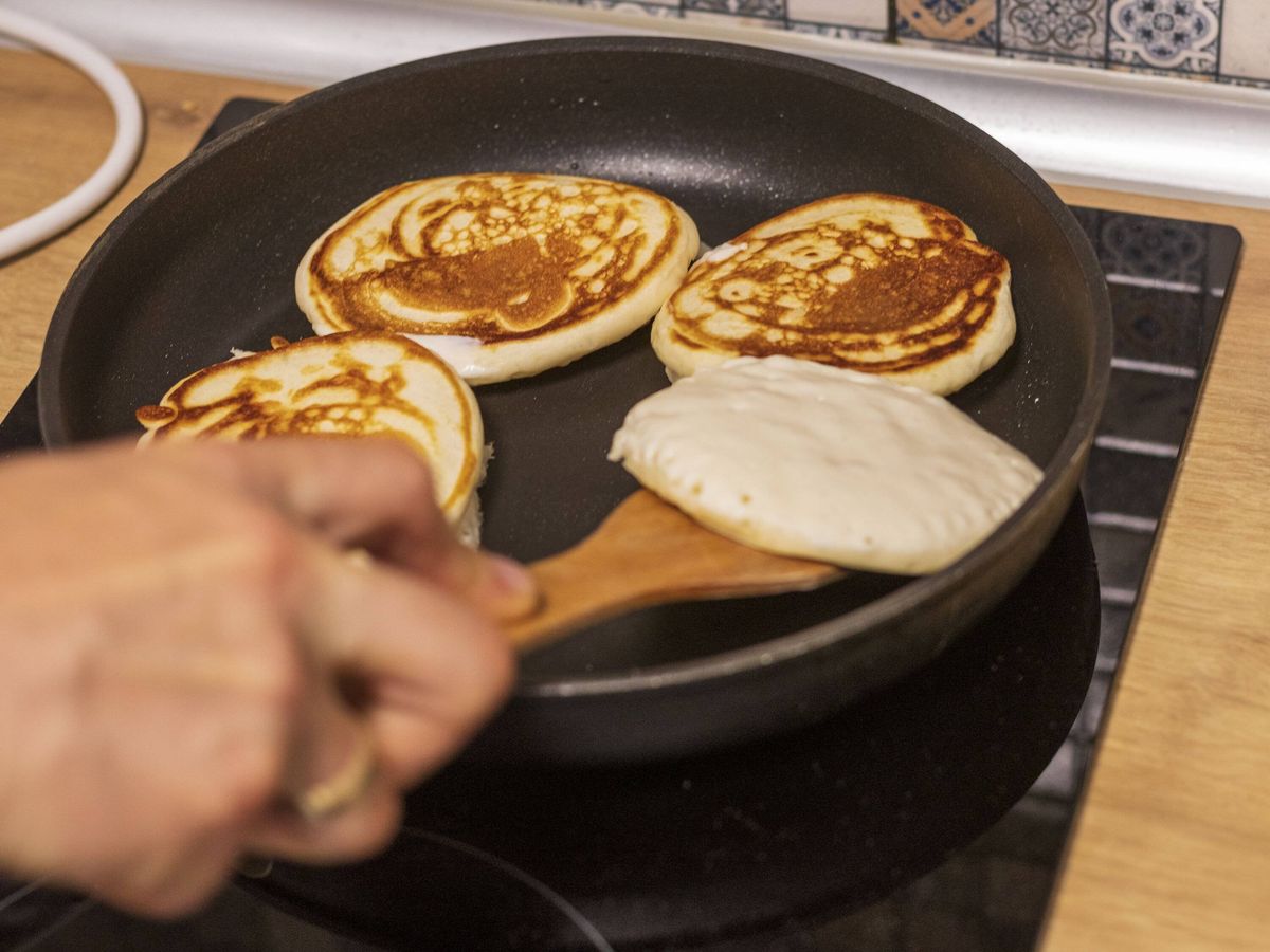 Woman flipping pancakes on frying pan. Food