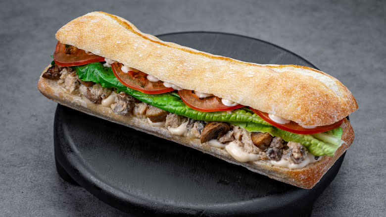 A tuna sandwich with lettuce, mushrooms and tomatoes.