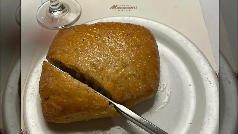 Knife slicing into loaf of Macaroni Grill's signature rosemary bread.