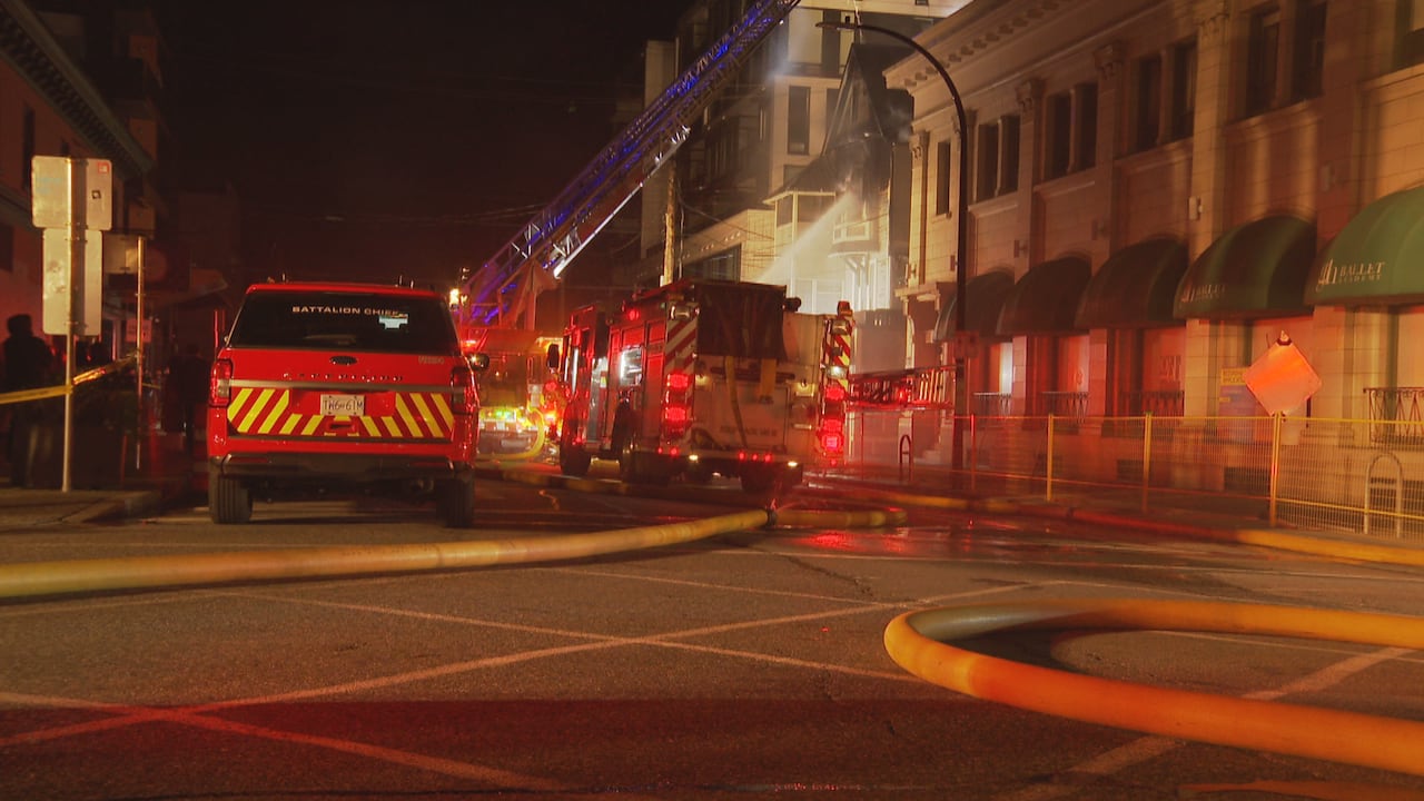 Fire trucks and hoses are seen on a deserted street.