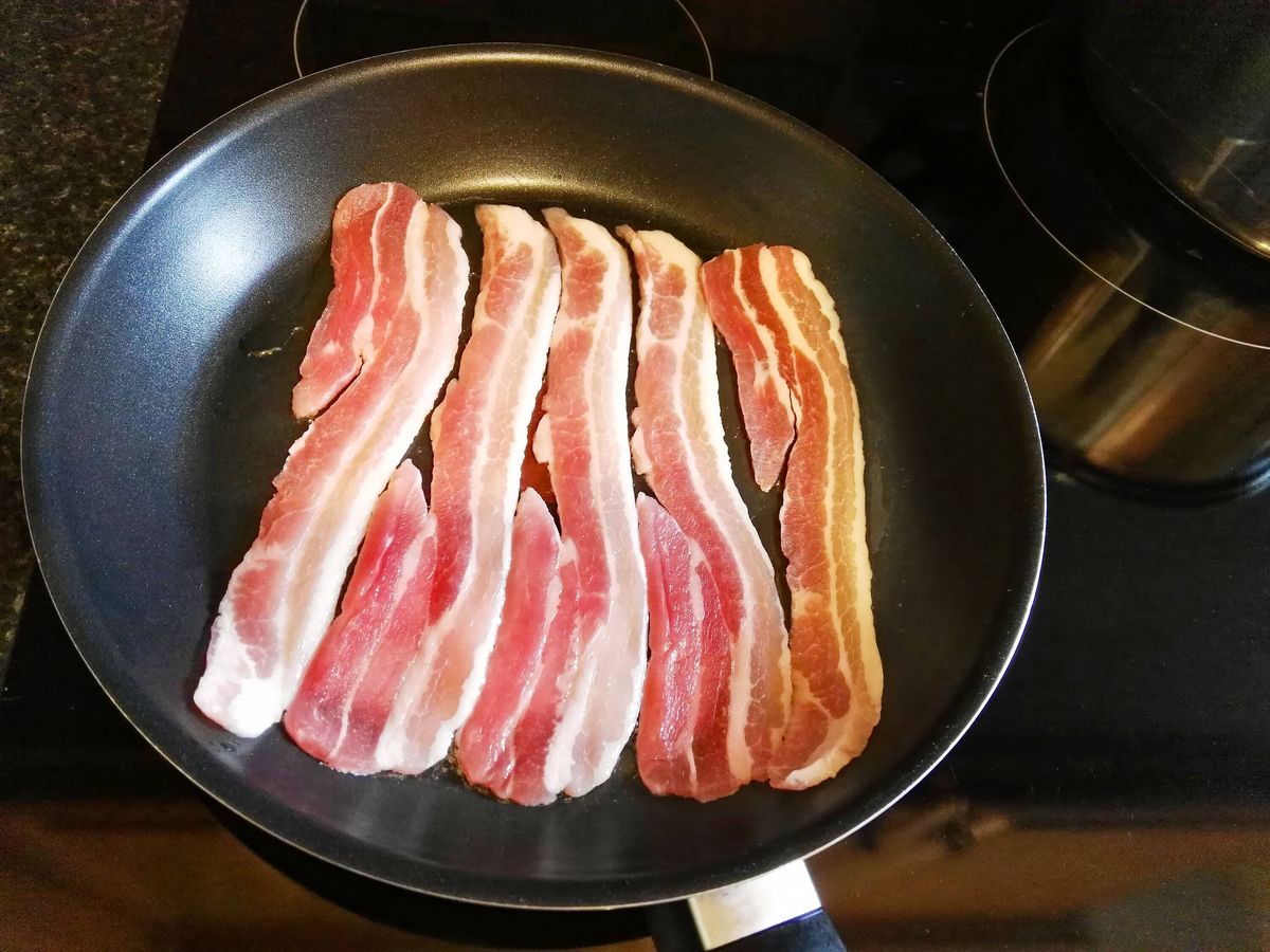 Bacon rashers in cold frying pan for breakfast.