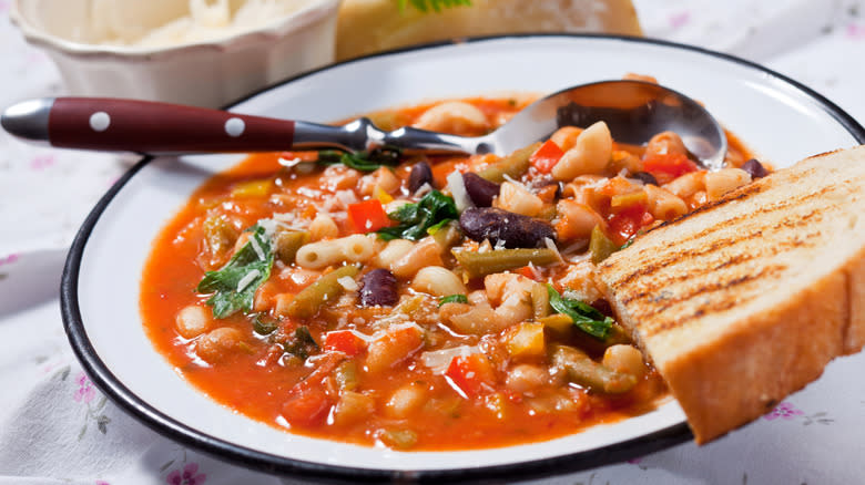 bowl of minestrone with bread on table