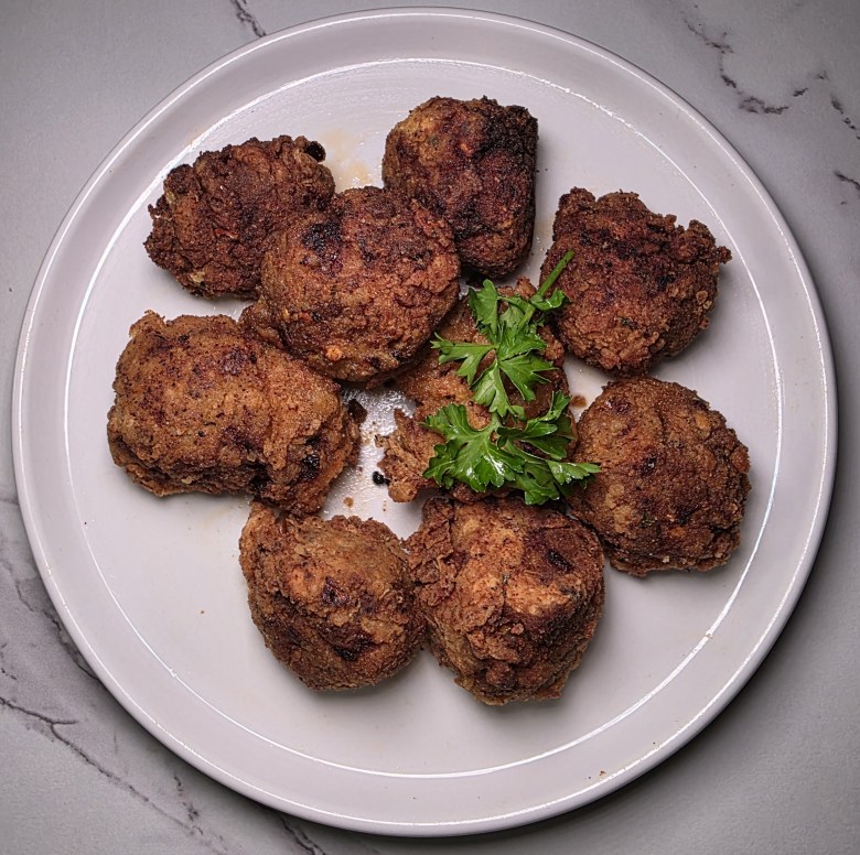 A traditional plate of Haitian staple food such as griot, fried green plantains, salad and pikliz. Boulèt is not pictured. Photo by Guethshina Altena/The Haitian Times.