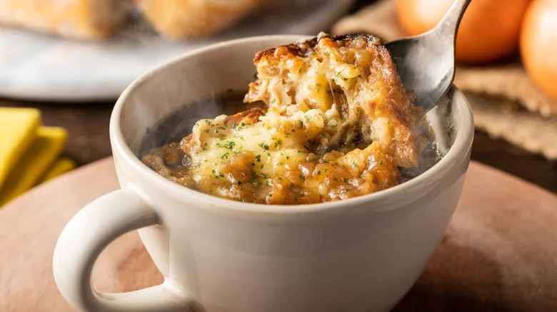 French onion soup being spooned out of a mug