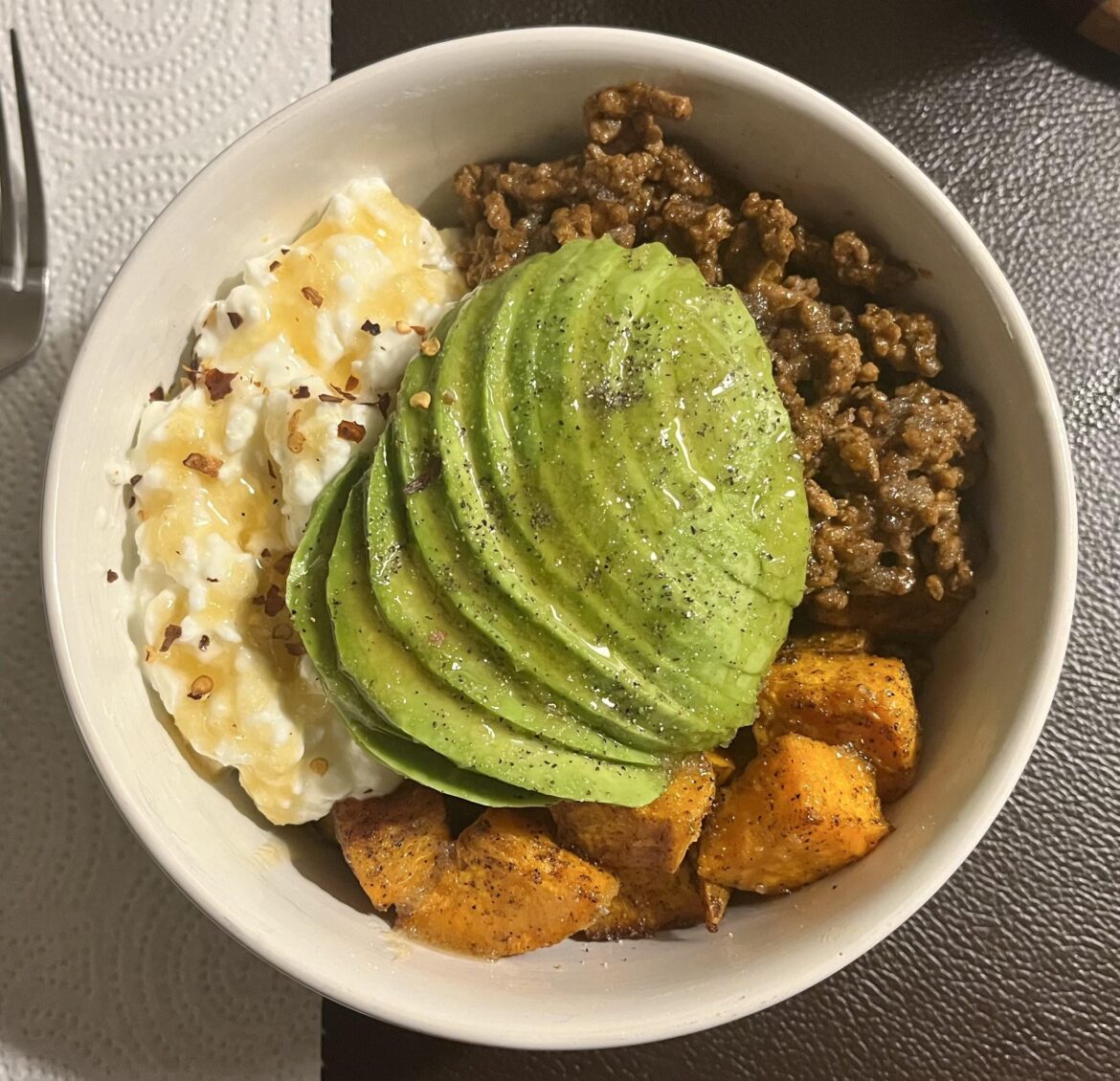 Ground beef and roasted sweet potato bowl with cottage cheese, avocado, and hot honey