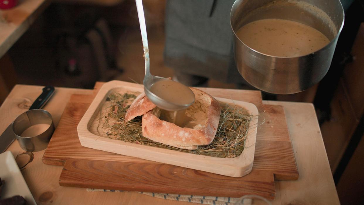 Franz Mulser serves his signature hay soup in a loaf of homemade bread, inside the hut of his restaurant Gostner Schwaige.