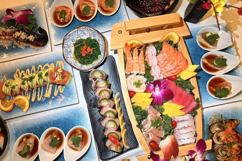 Sushi, chicken and bubble tea: 6 new restaurants from Round Rock to San Marcos Overhead view of an elaborate spread of Asian cuisine featuring sushi rolls, colorful banchan in small dishes, and various appetizers arranged on blue serving trays.