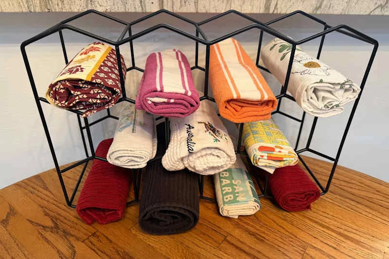 Kitchen towels rolled and organized in wine rack.