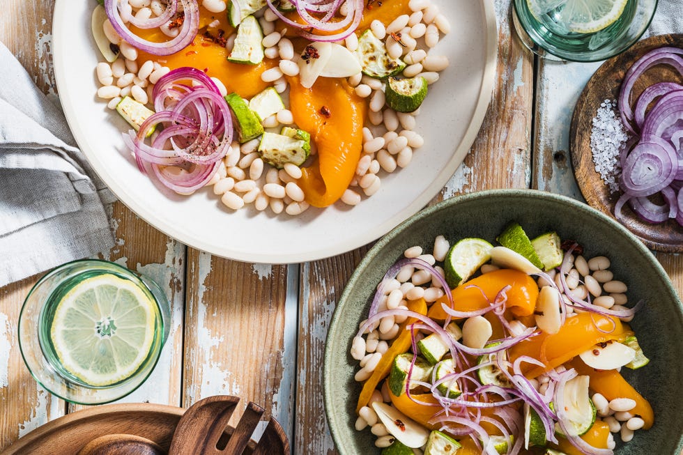 healthy vegan salad with orange bell pepper, white beans, zucchini, pickled red onion, table for two